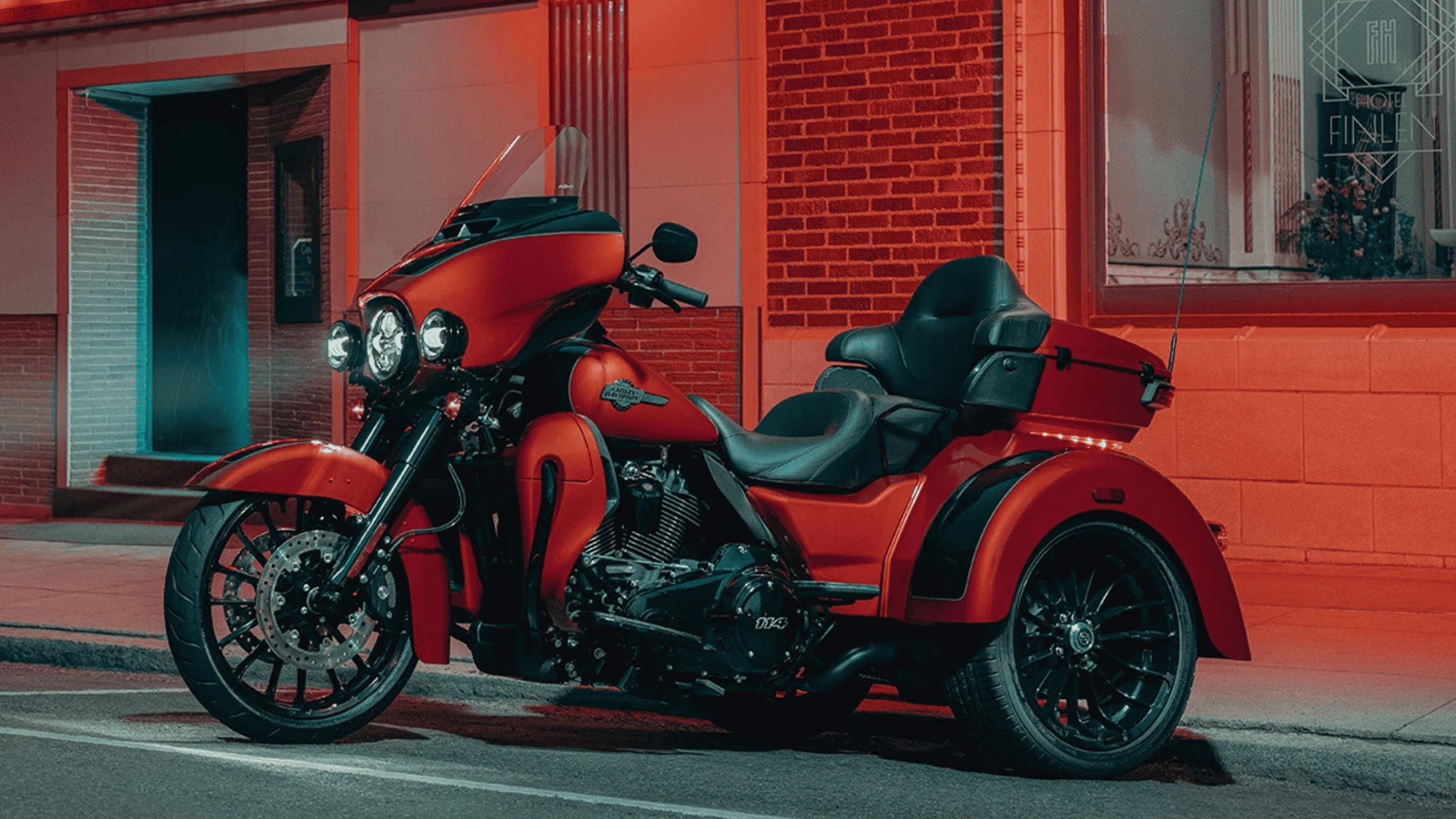 2025 Harley-Davidson Tri Glide Ultra trike in red parked under city street lighting.